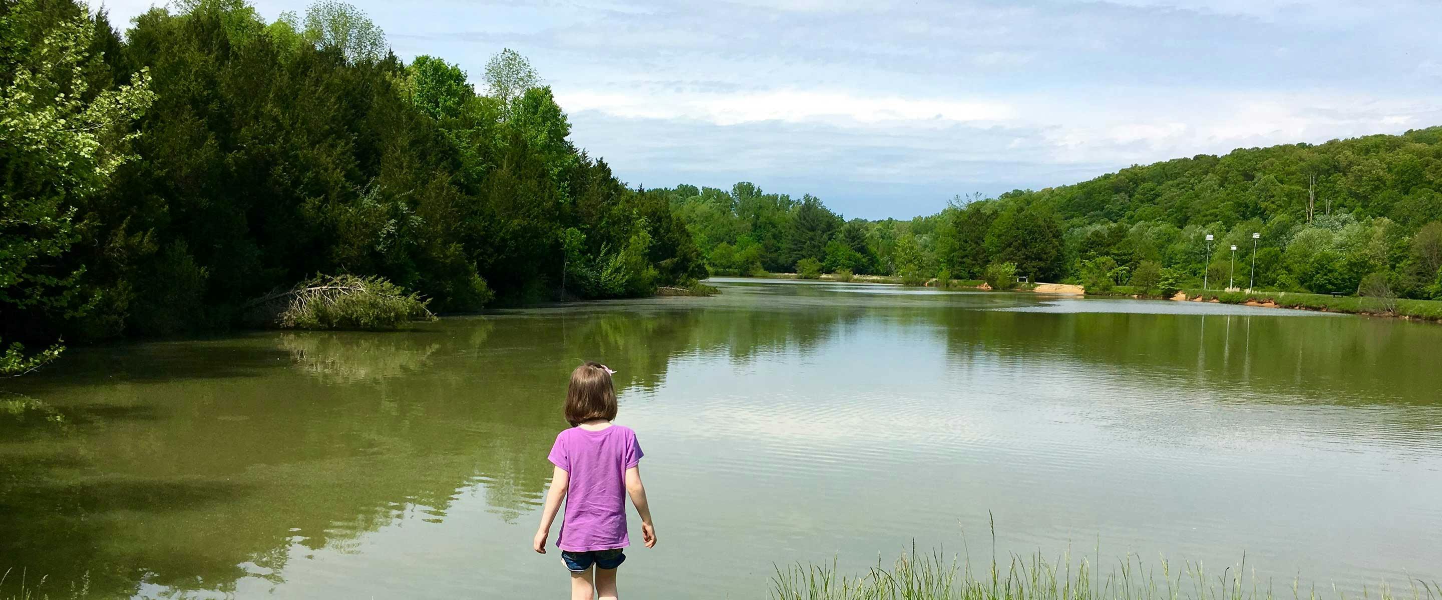 girl standing with her back to shop looking out over a beautiful serene lake at Hayswood Nature Preserve