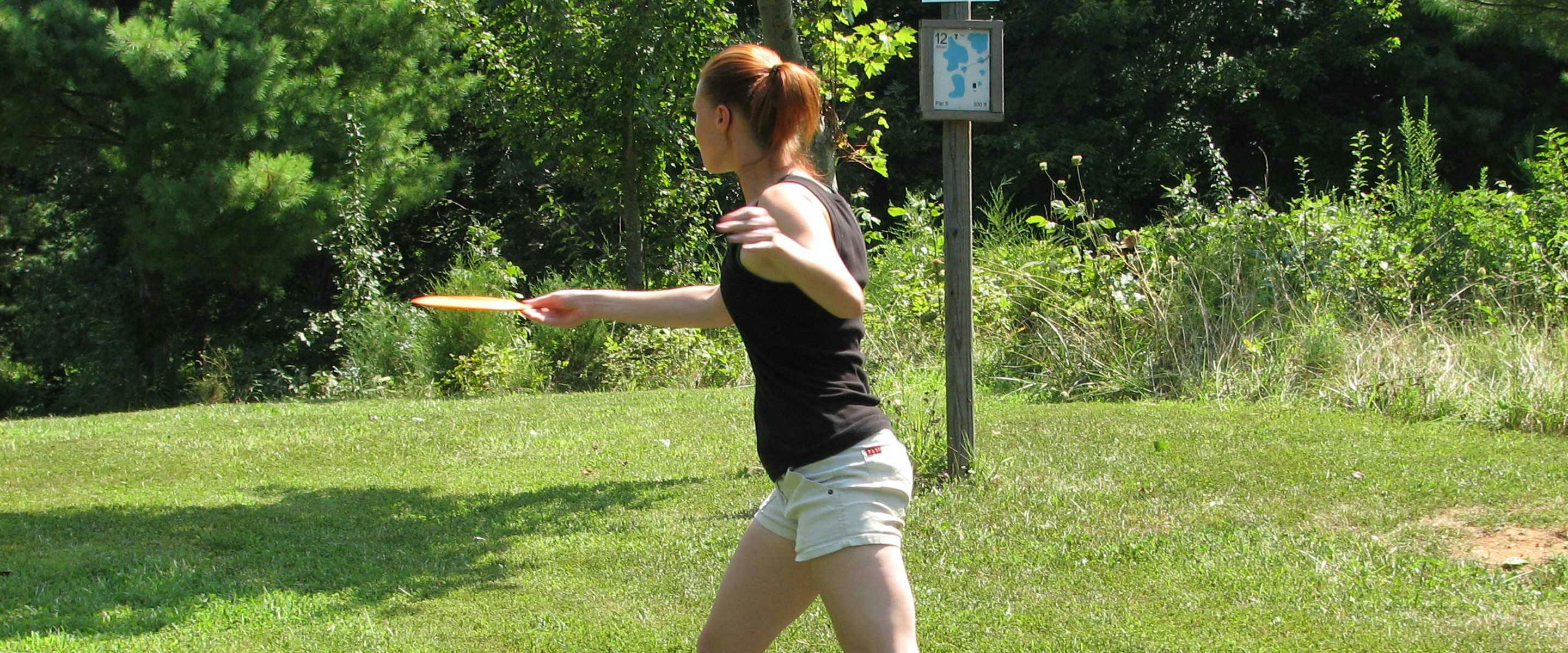 girl throwing frisbee on course